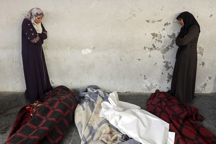 Mujeres palestinas junto a los cuerpos de familiares en el hospital árabe Al Ahli, en Gaza. · Foto: Omar Al-Qattaa, AFP