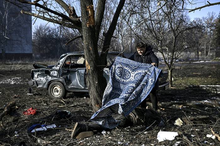 Un hombre cubre a una víctima de bombardeos rusos en la ciudad de Chuguiv, este de Ucrania. · Foto: Aris Messinis, AFP