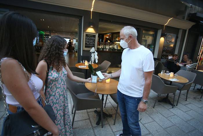 Verificación de los pases de salud de covid-19 a los clientes al ingresar a un restaurante, en la isla mediterránea francesa de Córcega. · Foto: Pascal Pochard-Casabianca, AFP