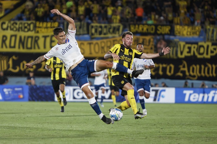 Emiliano Velázquez, de Nacional, y Ángel González, de Peñarol, durante un partido de la Serie Río de la Plata, en el estadio Centenario (archivo, enero de 2024). · Foto: Camilo dos Santos