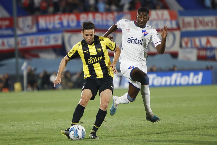 Camilo Mayada, de Peñarol, y Gonzalo Carneiro, de Nacional, durante el partido clásico en el Torneo Serie Río de la Plata, en el estadio Centenario (archivo, enero de 2024). · Foto: Camilo dos Santos