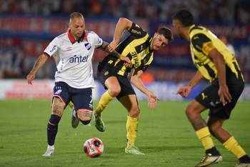Nicolás López, de Nacional, y Rodrigo Pérez, de Peñarol, el 26 de enero, en el estadio Centenario. · Foto: Gianni Schiaffarino