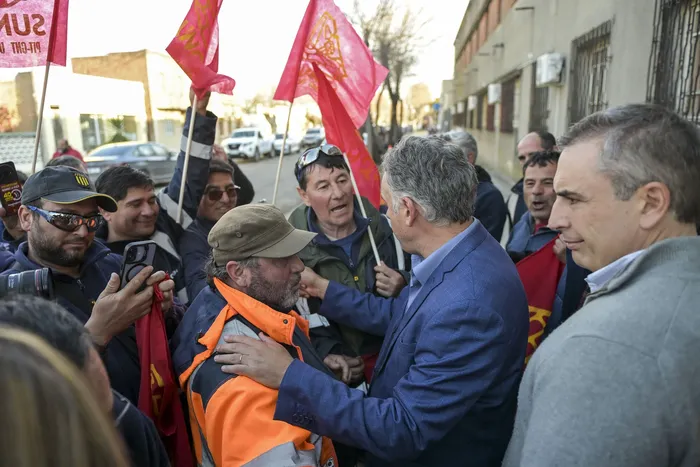 Yamandú Orsi junto a trabajadores del Sunca que lo esperaban fuera del evento donde se presentó la reformulación del proyecto de saneamiento para Juan Lacaze, el 9 de julio, en el Centro Cultural Don Bosco. · Foto: Ignacio Dotti