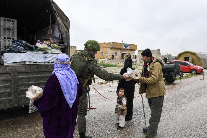 Soldado ruso reparte ayuda alimentaria a civiles sirios mientras cruzan desde áreas controladas por los rebeldes en la provincia de Idlib hacia territorios controlados por el régimen, el 27 de diciembre de 2018. · Foto: George Ourfalian / AFP