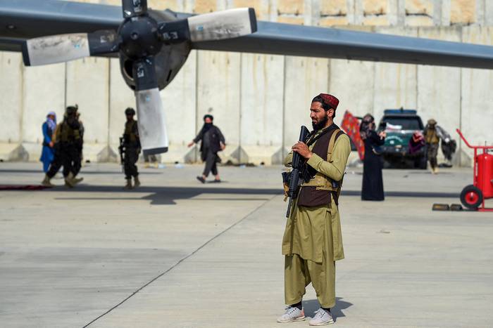 Talibanes montan guardia cerca de un avión de la Fuerza Aérea afgana, este martes, en el aeropuerto de Kabul. · Foto: Wakil Kohsar, AFP
