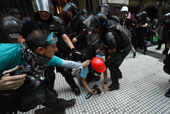 La Policía Antidisturbios se enfrenta a fotoperiodistas durante una protesta de jubilados apoyada por hinchas de fútbol, el miércoles, en Buenos Aires. · Foto: Luis Robayo, AFP