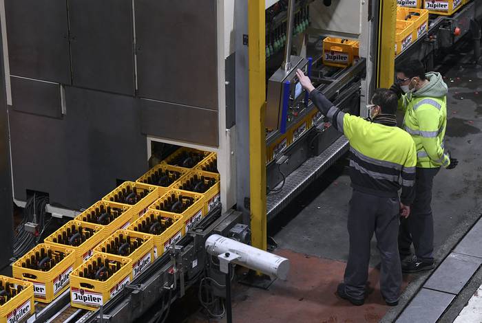 Trabajadores en una planta de producción de botellas reutilizables en la cervecería Stella Artois, en Lovaina, el 8 de febrero. · Foto: John Thys, AFP