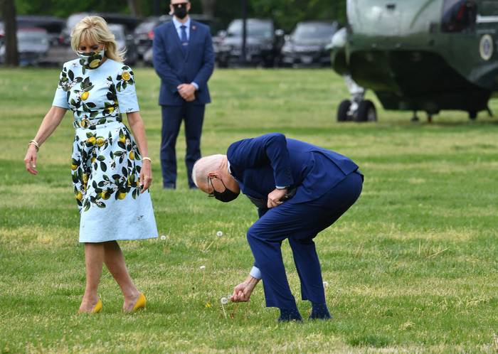 Joe Biden recoge una flor para la primera dama Jill Biden, mientras se dirigen al helicóptero Marine One, en Washington. · Foto: Nicholas Kamm
