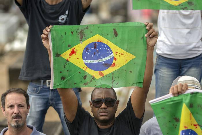 Amigos y parientes del músico brasileño Evaldo dos Santos, asesinado por una unidad militar que lo confundió con un delincuente, muestran banderas ensangrentadas frente a la sede de un regimiento en Río de Janeiro, el 10 de abril. · Foto: Mauro Pimentel