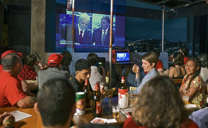 El debate presidencial se proyecta en un edificio frente a un bar, el domingo, en Río de Janeiro. · Foto: Carl de Souza, AFP