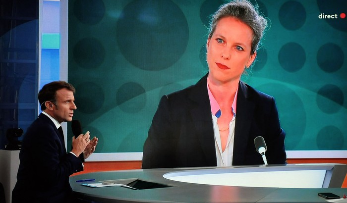 La televisión transmite al presidente de Francia, Emmanuel Macron, durante a una entrevista en vivo con un retrato de Lucie Castets. · Foto: Ludovic Marin, AFP