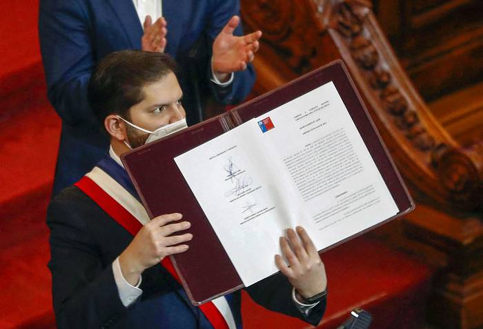 Gabriel Boric muestra el borrador final de la propuesta constitucional luego de firmarla durante su presentación en el Congreso Nacional en Santiago (04.07.2022). · Foto: Javier Torres AFP