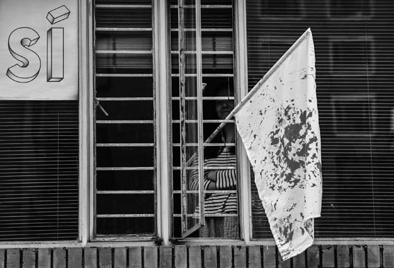 Una mujer coloca una bandera blanca salpicada de rojo, en Bogotá. Foto: Luis Acosta, AFP.