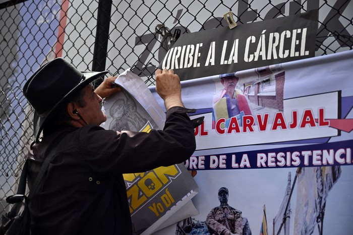 Un hombre pide el encarcelamiento del expresidente colombiano Álvaro Uribe durante su juicio, el 28 de julio, frente al Complejo Judicial de Paloquemao en Bogotá. · Foto: Raúl Arboleda, AFP
