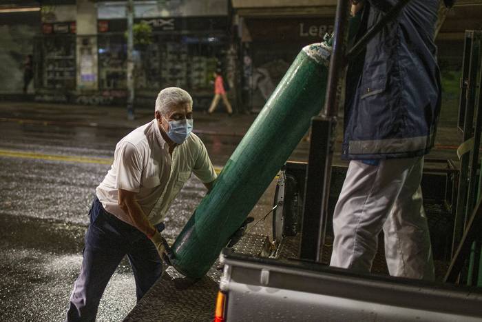 Trabajadores de la salud llevan tanques de oxigeno a domicilio, el 3 de mayo, en el centro de Montevideo. · Foto: .