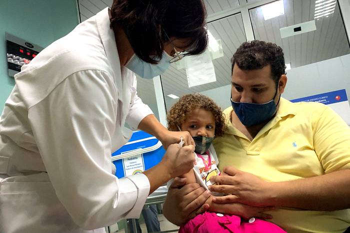 Pedro Montano sostiene a su hija Roxana, de 3 años, mientras es vacunada contra el COVID-19 con la vacuna cubana Soberana Plus, el 24 de agosto, en el hospital Juan Manuel Márquez de La Habana. · Foto: Adalberto Roque, AFP