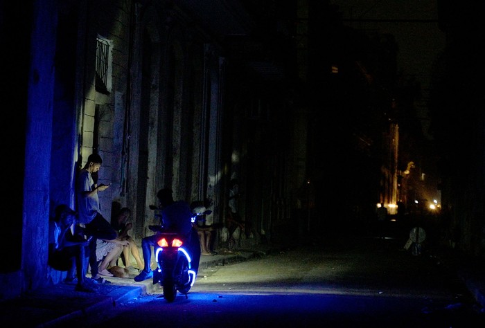 Cubanos utilizan una moto para iluminar una calle, el 19 de octubre, durante el segundo día de apagón nacional en La Habana. · Foto: Adalberto Roque, AFP