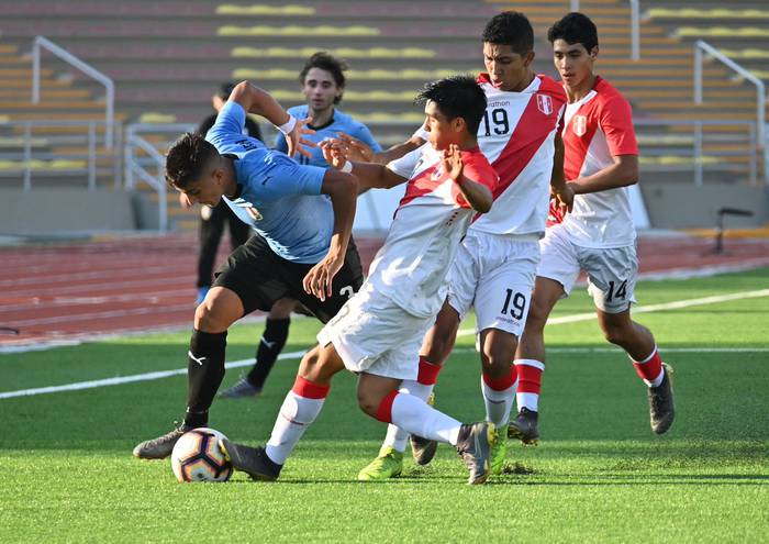 Cristian Olivera, de Uruguay, entre jugadores de Perú, en el Sudamericano sub 17, en Lima. Foto: AUF.