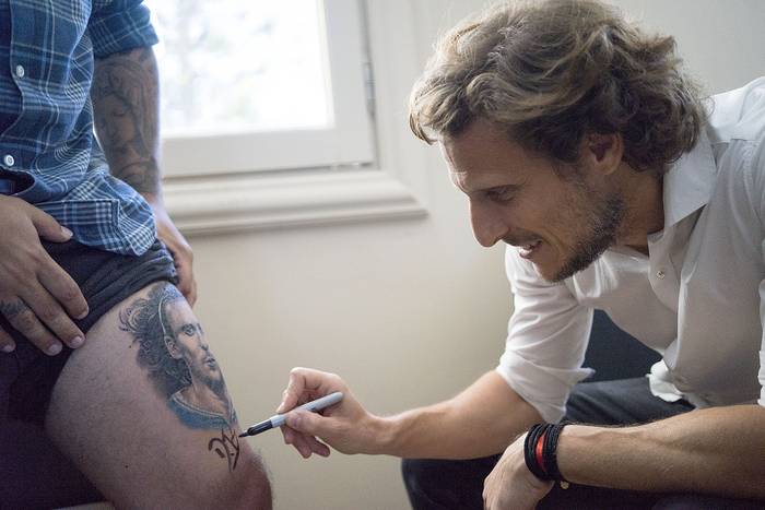 Diego Forlán mientras firma el tatuaje de un fan. · Foto: Mariana Greif