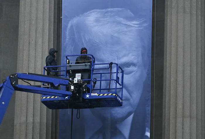 Instalación de un cartel con la imagen de Donald Trump, en la fachada de la sede del Departamento de Justicia de Estados Unidos, el 19 de febrero en Washington DC. · Foto: Brendan Smialowski, AFP