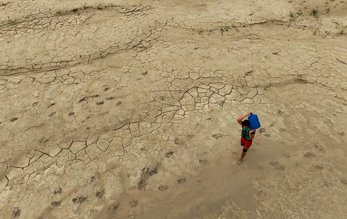 Una persona transporta un bidón de agua en un banco de arena del río Madeira, en la comunidad Paraizinho, Amazonas, Brasil. · Foto: Michael Dantas, AFP