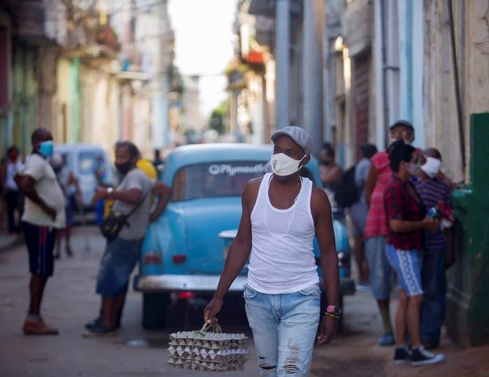 Un hombre camina por una calle con cubetas de huevos en La Habana. · Foto: Yander Zamora, EFE