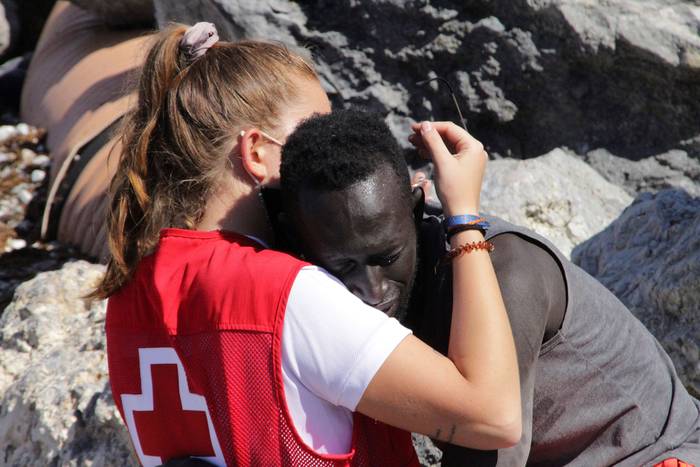 Una trabajadora de la Cruz Roja y un inmigrante que ha logrado cruzar uno de los espigones fronterizos, ayer, en Ceuta.
 · Foto: Reduan, EFE