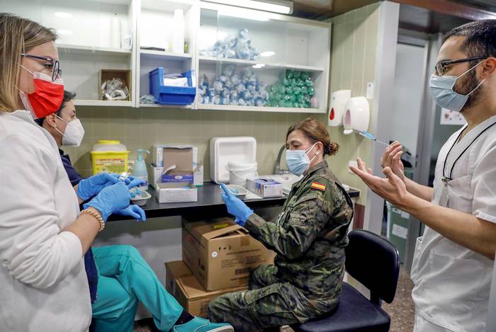 Una militar prepara, junto al personal del Hospital Clínico de Valencia, las dosis de la vacuna contra la covid-19. · Foto: Juan Carlos Cardenas, EFE