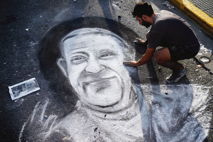 Javier Sativa, artista argentino, dibuja el rostro del papa Francisco en una calle frente a la entrada de la Catedral de Buenos Aires el 21 de abril. · Foto: Luis Robayo, AFP