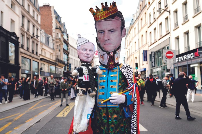 Protesta, con máscara de Emmanuel Macron y marioneta de Michel Barnier, en las calles de París, Francia, el 21 de setiembre. · Foto: Dimitar Dilkoff / AFP