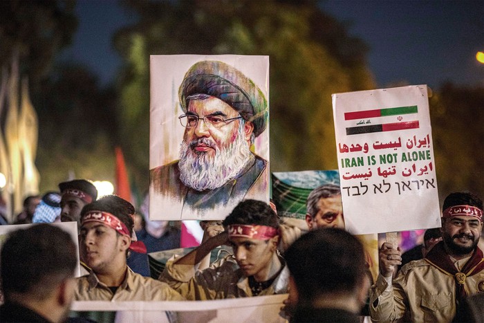 La imagen del líder de Hezbollah libanés, Hassan Nasrallah, durante una vigilia en honor a los fallecidos del Cuerpo de la Guardia Revolucionaria Islámica y científicos iraníes en los ataques aéreos israelíes, frente a la sede de la embajada iraní en Bagdad, el 28 de junio. · Foto: Murtadha Ridha / AFP