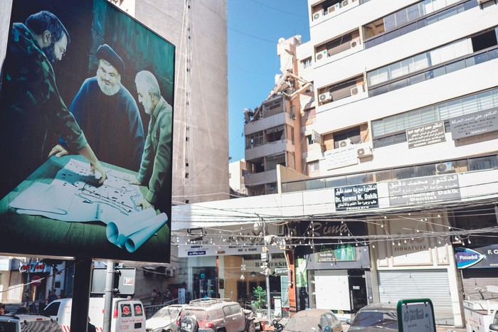 Cartel con la imagen de Qasem Soleimani y Hassan Nasrallah frente al edificio blanco del ataque militar israelí en los suburbios del sur de Beirut, el 31 de julio. · Foto: Anwar Amro, AFP.