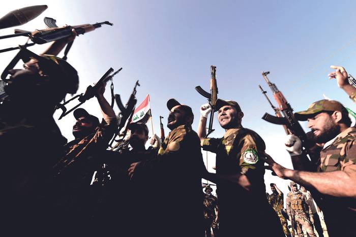 Combatientes de Al-Hashd Al-Sha'abi integrados en las fuerzas armadas iraquíes, durante un desfile del noveno aniversario de su fundación, en la región de al-Hadar, norte de Irak, el 22 de junio. · Foto: Zaid Al-Obeidi / AFP