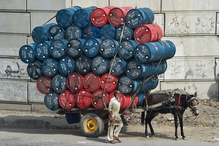 Carga de bidones de petróleo en una calle de Lahore, Pakistán. · Foto: Arif Ali, AFP