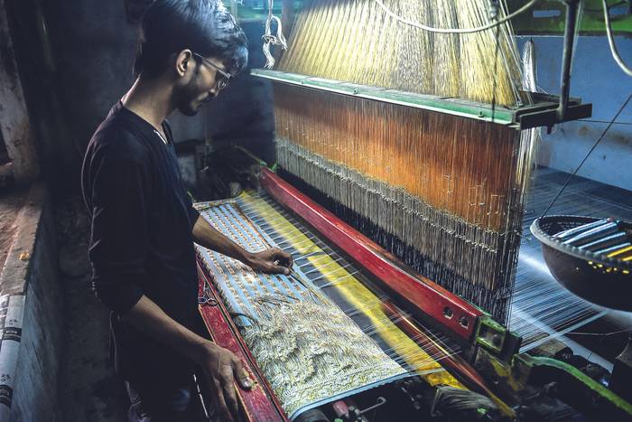 Durante la confección de un sari, vestido tradicional de las mujeres, en una fábrica en Karachi, la ciudad más poblada de Pakistán, setiembre de 2021. · Foto: Rizwan Tabassum, AFP