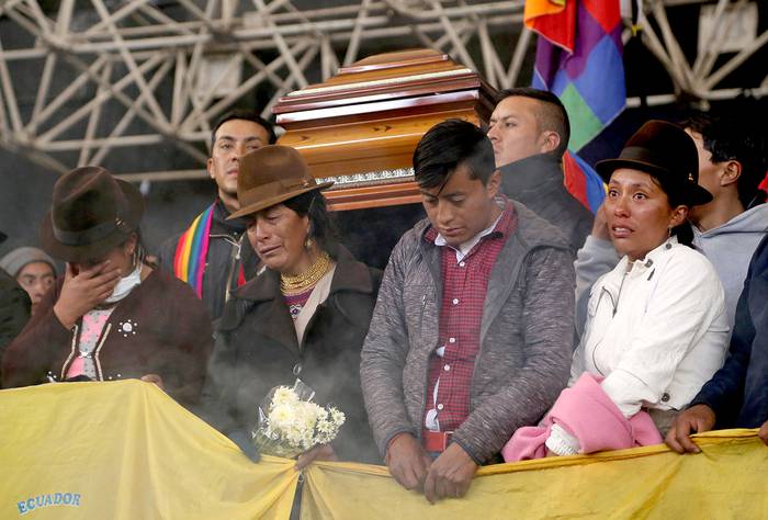Oficiales de Policía que permanecen retenidos cargan el féretro del líder indígena Inocencio Tucumbi, muerto durante enfrentamientos ocurridos ayer en la Casa de la Cultura de Quito, en Ecuador.
 · Foto: Cristina Vega, AFP