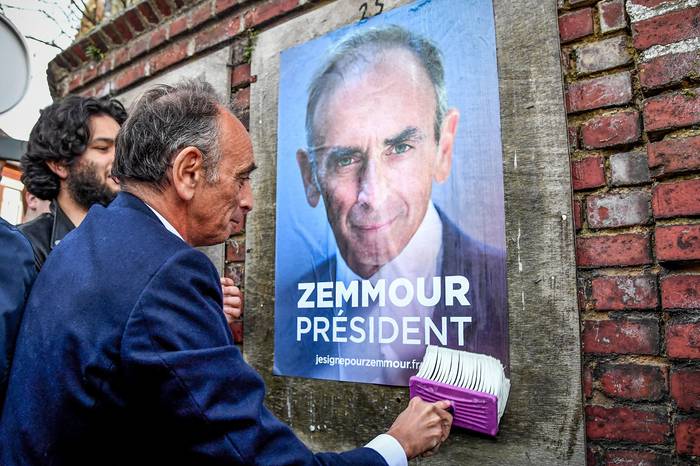Eric Zemmour, candidato presidencial francés, pega un cartel de campaña durante una visita, el 14 de enero, al pueblo de Honnecourt-sur-Escaut, en el norte de Francia. · Foto: Bertrand Guay, AFP
