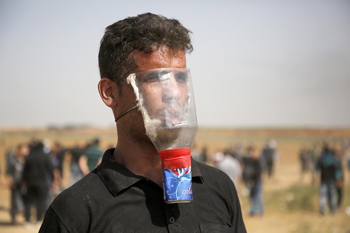 Un manifestante palestino se cubre para protegerse del gas lacrimógeno durante los enfrentamientos con las fuerzas de seguridad israelíes, ayer en Gaza. Foto: Mohammed Abed, AFP