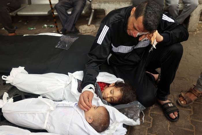 El palestino Ashraf y los cuerpos de sus dos hijas, Aysal y Rashel, después de que murieran en un ataque aéreo israelí nocturno, el 4 de abril, en el hospital al-Najar, en Rafah, Franja de Gaza. · Foto: Mohammed Abed, AFP