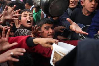 Niños palestinos desplazados esperan una ración de comida preparada, el 9 de marzo, en un comedor benéfico en Beit Lahia, en el norte de la Franja de Gaza. · Foto: Omar Al-Qattaa, AFP