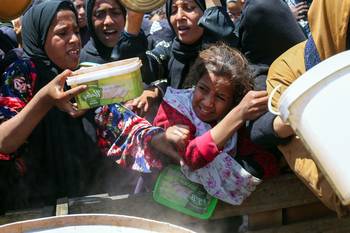 Palestinos esperan una ración de comida caliente en un campo de refugiados de Nuseirat, el 5 de mayo, en el centro de la Franja de Gaza. · Foto: Eyad Baba, AFP