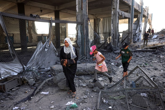 Palestinos desplazados caminan entre los escombros de un depósito de ayuda humanitaria y un refugio de la UNRWA, tras un ataque israelí, el 10 de mayo, en Jabalia, en el norte de la Franja de Gaza. · Foto: Bashar Taleb, AFP