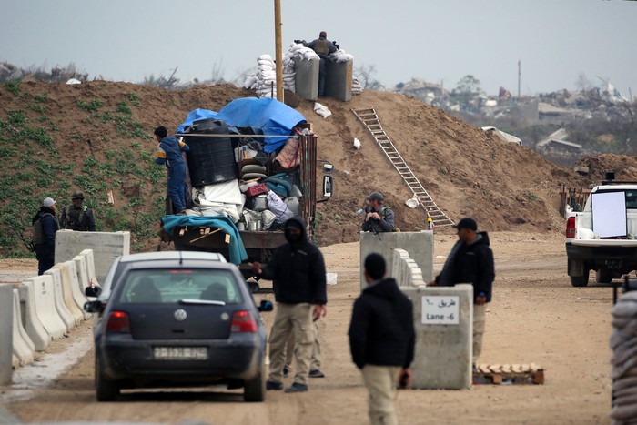 Palestinos cruzan un puesto de control vigilado por fuerzas de seguridad egipcias y estadounidenses en la carretera de Saladino en Al Mughraqa, el 10 de febrero, mientras se desplazan hacia las zonas del norte de Gaza. · Foto: Eyad Baba, AFP