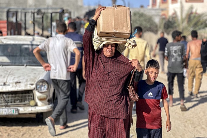 Palestinos desplazados con paquetes de alimentos repartidos por una fundación respaldada por Estados Unidos, el 27 de mayo, en Rafah, en el sur de la Franja de Gaza. · Foto: AFP