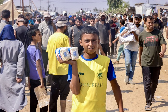 Joven palestino con bolsas de harina recibidas, ayer, en el corredor de Rafah, Franja de Gaza. · Foto: AFP