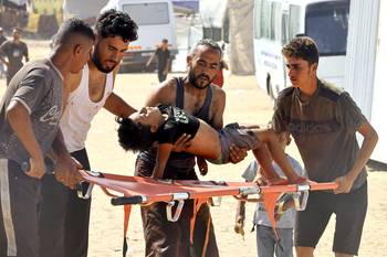 Un niño palestino herido por disparos israelíes mientras buscaba ayuda humanitaria en el corredor de Rafah, es trasladado, el 30 de julio, a un hospital de campaña en el sur de la Franja de Gaza. · Foto: AFP