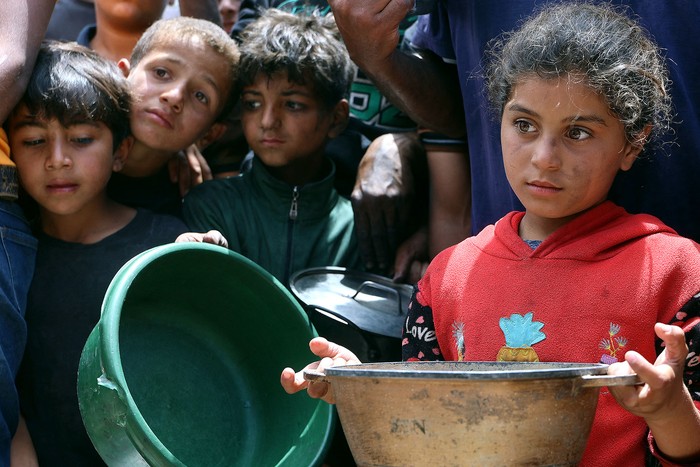 Niños palestinos esperan frente a un camión de distribución de comida caliente en un campamento de desplazados, el 22 de mayo, cerca del puerto de la ciudad de Gaza. · Foto: Omar Al-Qattaa, AFP