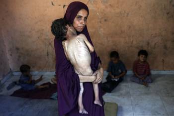 Naeema, madre palestina de 30 años, con su hijo Yazan, de 2 años, en su casa dañada, el 23 de julio, en el campo de refugiados de Al-Shati, al oeste de la ciudad de Gaza. · Foto: Omar Al-Qattaa, AFP