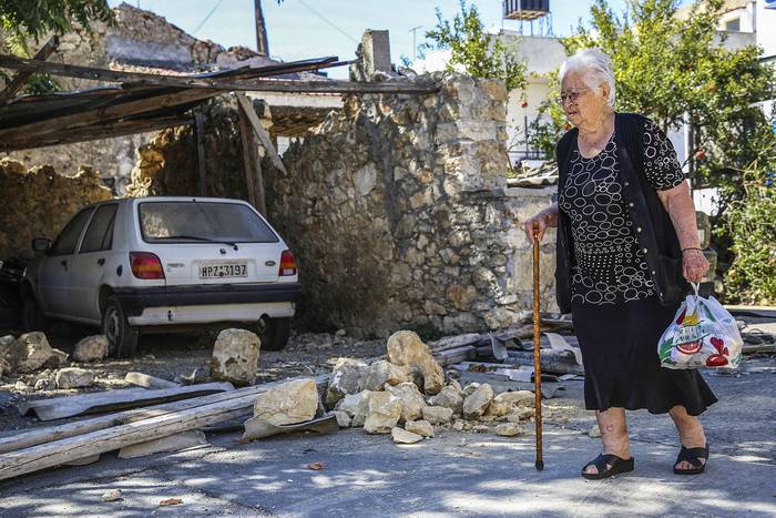 Una vecina pasa junto a una casa derrumbada por un terremoto, este lunes, en la aldea de Arkalochori en la isla de Creta, Grecia. · Foto: Costas Metaxakis, AFP