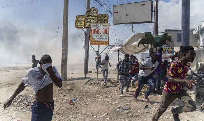 Manifestantes huyen de los gases lacrimógenos lanzados por la policía en Puerto Príncipe, durante una protesta contra el gobierno. · Foto: Richard Pierrin, AFP